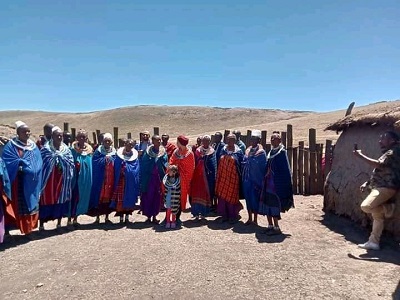 Maasai tribe members in traditional attire standing in a lush green savannah landscape, showcasing their vibrant red shukas and intricate beadwork